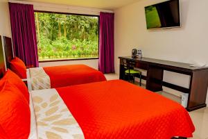 um quarto com 2 camas, uma secretária e uma janela em Hotel Los Rios em Guácimo