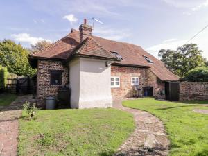 a small brick house with a grass yard at Brew Cottage in Chislet