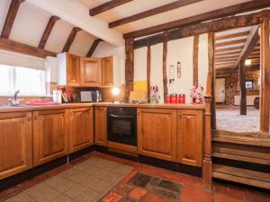 eine Küche mit Holzschränken und einem schwarzen Geschirrspüler in der Unterkunft Brew Cottage in Chislet + 19 Fotos