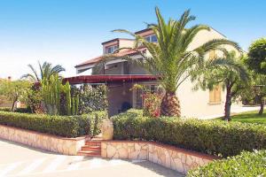 a house with a palm tree in front of it at Residence Fontana Barone, Cefalu in Cefalù