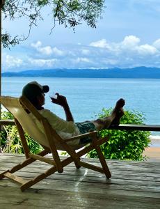 un hombre tendido en una silla de jardín en la playa en Choibana Ecolodge, en Bahía Solano