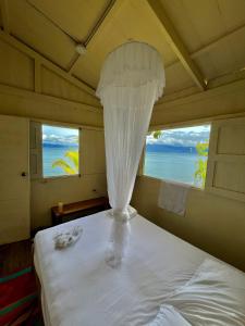 a bedroom with a white bed with a view of the ocean at Choibana Ecolodge in Bahía Solano