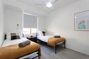 two beds in a room with white walls and a window at Living on Lennard - Pet friendly house close to CBD in Perth