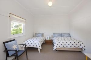 a bedroom with two beds and a chair and a window at Salamanca in Lorne