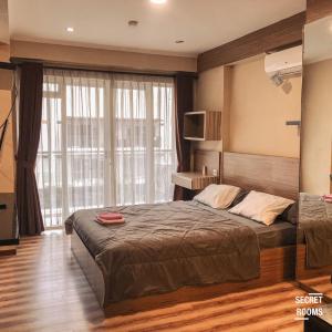 a bedroom with a bed and a large window at Gateway Pasteur Apartment by Secret Rooms in Bandung