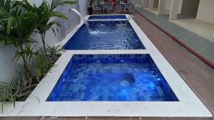 una piscina con azulejos azules en un edificio en Lindo apartamento pé na areia em Cabo Gaibú prox Porto de galinhas en Cabo de Santo Agostinho