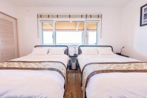 two twin beds in a room with a window at Sunset Villa Awaji in Awaji