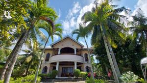 a house with palm trees in front of it at Private beachfront house with ocean view and direct reef access in Moalboal