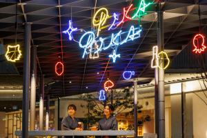 大阪的住宿－OMO7 Osaka by Hoshino Resorts，两个妇女站在一间商店前面,有 ⁇ 虹灯标志