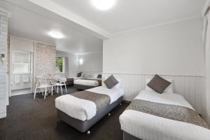 a hotel room with two beds and a table at Coach House Launceston in Launceston