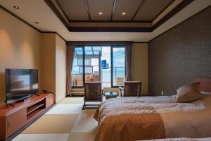 a bedroom with a bed and a flat screen tv at Isoaruki no Yuyado Ushiogumo -6 years or older- in Kawazu