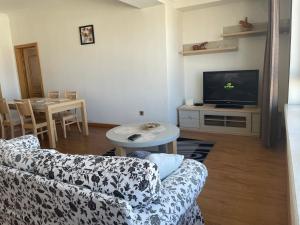 ein Wohnzimmer mit einem Sofa, einem TV und einem Tisch in der Unterkunft Lovely 2 BR unit with city view in Ulaanbaatar