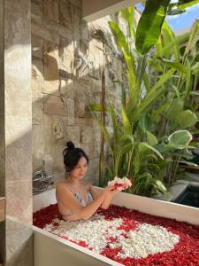 a woman sitting in a bath tub with flowers at Danka Villa Sanur in Sanur