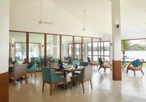 a dining room with tables and chairs and windows at Marina by DAE in Piliyandala