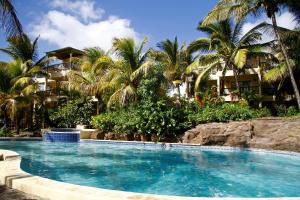 a swimming pool in front of a resort with palm trees at Hibiscus Boutique Hotel in Pereybere