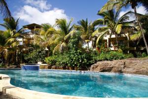 einen Pool vor einem Resort mit Palmen in der Unterkunft Hibiscus Boutique Hotel in Pereybere