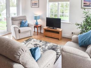 sala de estar con 2 sillas y TV de pantalla plana en The Coach House - Uk41070 en Wootton Bridge