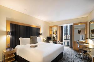 um quarto de hotel com uma cama grande e uma secretária em Sofitel Sydney Wentworth em Sidney