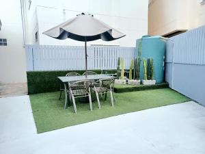 a table and chairs with an umbrella on a patch of grass at Near boxing center, 1BR apartment, Sofa bed, Wifi in Chalong 