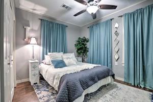 a bedroom with a bed with blue curtains and a ceiling fan at Historic Galveston Home Walkable Neighborhood! in Galveston