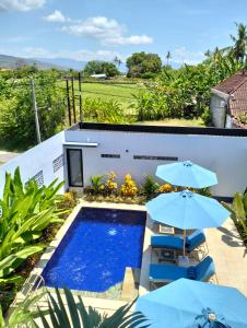 una piscina con 2 sombrillas junto a una casa en Villa Bintang, en Lovina
