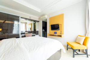 um quarto com uma cama branca e uma cadeira amarela em Singgahsini Casa D Elok Near PIM 1 em Jakarta