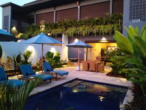 un patio con sillas y sombrillas junto a una piscina en Villa Bintang, en Lovina