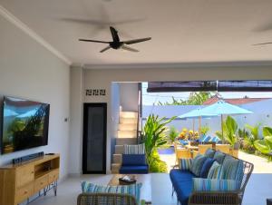 sala de estar con sofá azul y ventilador de techo en Villa Bintang, en Lovina