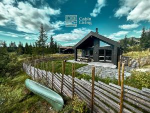 Modern unique cabin fantastic location Skeikampen في Svingvoll: كابينة صغيرة بها زورق أمام السياج