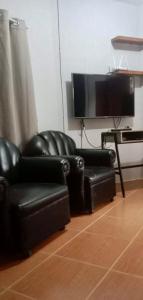 2 sillas de cuero negro y sala de estar con TV en Affordable Staycation Home for 2-3 People! en Dauin