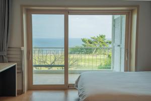 a bedroom with a sliding glass door with a view of the ocean at Seaore Resort in Seogwipo +42 photos