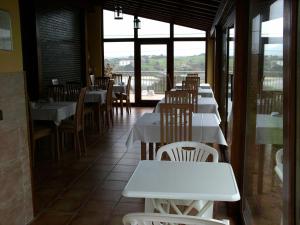a restaurant with white tables and chairs and a window at Hotel Azul de Galimar in San Vicente de la Barquera