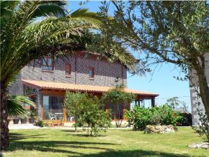 a house with a palm tree in front of it at Hotel Azul de Galimar in San Vicente de la Barquera