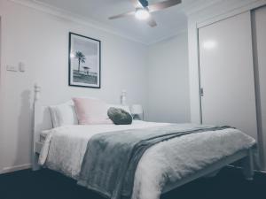 ein weißes Schlafzimmer mit einem Bett und einem Deckenventilator in der Unterkunft The Coastal Nest in Sussex inlet