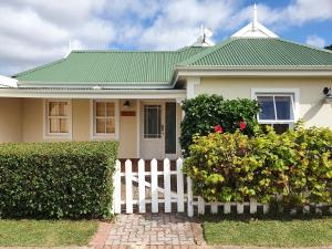 a white fence in front of a house with a green roof at 4236 River Club in Plettenberg Bay
