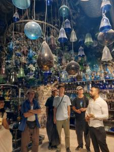 un grupo de personas de pie frente a una habitación llena de lámparas de cristal en Friends Hostel.Area B, en Hebron
