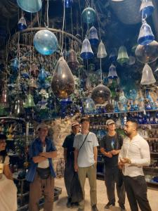 a group of people standing in front of a room filled with glass lamps at Friends Hostel.Area B in Hebron