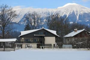 una casa cubierta de nieve con montañas en el fondo en Guest House Golja en Bled