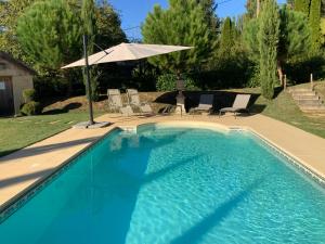 een zwembad met stoelen en een parasol bij Amity. Exclusive poolside garden apartment in Sarlat-la-Canéda