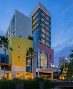 een hoog gebouw met een kleurrijke gevel en palmbomen bij ARTOTEL TS Suites Surabaya in Wonokromo
