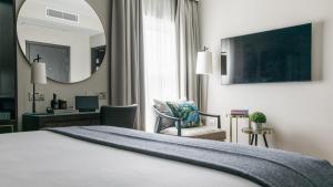 a hotel room with a bed and a desk and a mirror at The Selwyn, Richmond in Richmond upon Thames