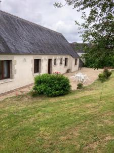 a white house with two white chairs in a yard at Maison de campagne de plein pied. in Plougonven