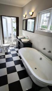 La salle de bains est pourvue d'une grande baignoire et de 2 lavabos. dans l'établissement Fifty Five on Park, à Graaff-Reinet