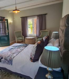 - une chambre avec un lit, deux chaises et une fenêtre dans l'établissement Fifty Five on Park, à Graaff-Reinet