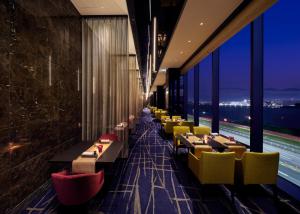 東京的住宿－Villa Fontaine Premier Haneda Airport，餐厅设有桌子和黄色的椅子以及窗户。