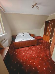 Ce lit se trouve dans une petite chambre dotée d'un tapis rouge. dans l'établissement Crocus, à Dragobrat