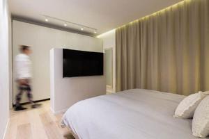 a bedroom with a bed and a flat screen tv at Taverna by HolyGuest in Tel Aviv
