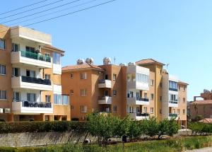 una fila de edificios de apartamentos con árboles en el primer plano en My sweet home en Pafos
