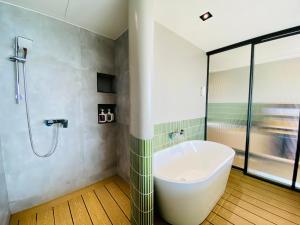 a bathroom with a tub and a shower at 厝True Hub旅店 in Nanwan