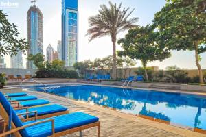 een zwembad met blauwe ligstoelen en hoge gebouwen bij bnbmehomes - Duplex Living walk to Burj K and Dubai Mall - L313 in Dubai